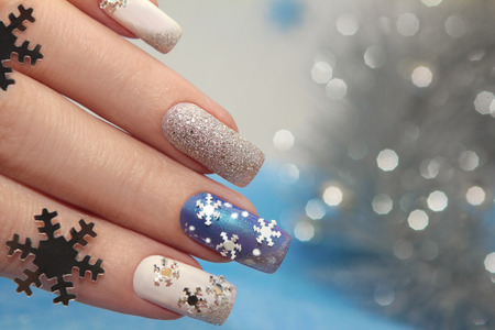 Manicure with snowflakes on your nails with colored lacquers on a rectangular shaped nails.の写真素材