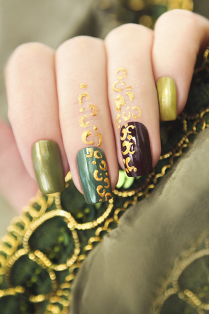 Green manicure with gold pattern on the nails and fingers model.の写真素材