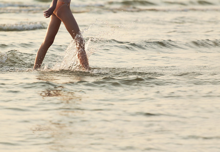 A young woman emerges from the sea after bathing in it at sunset in the summer.の写真素材
