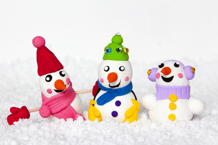 The collection of plasticine snowmen in different clothes on snow white background.の写真素材