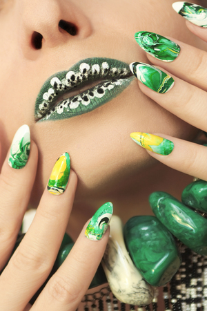 Stone blurred water manicure white, yellow, green and black nail Polish on oval acute form.Nail art.の写真素材
