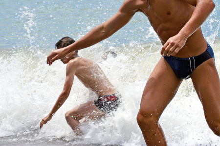 Two young people run out of the sea on the coast.の写真素材