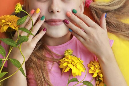 Bright and colorful children's manicure on the nails of girls with yellow flowers and good mood.の写真素材