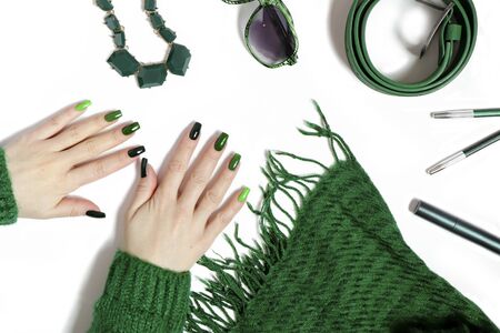 Fashionable green manicure on long nails and women's accessories in various shades of green on a white background.の写真素材