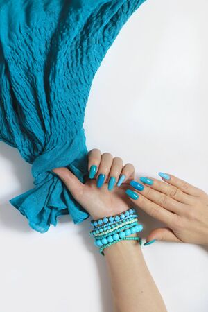 Fashionable oval long nails with different shades of nail polish from light blue to turquoise. Creative manicure on female hands with bracelets and a scarf.の写真素材