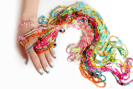 Beautiful French manicure with colorful dots on white nail polish and beaded jewelry on a woman's hand.の写真素材