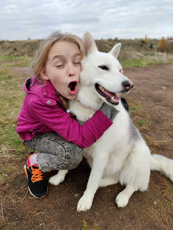 The girl happily communicates with her favorite dog in nature.の写真素材