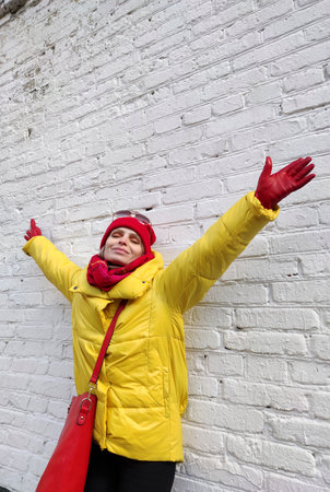 Young woman in a red-yellow fashionable image in sunglasses on a background of a white brick wall.の写真素材