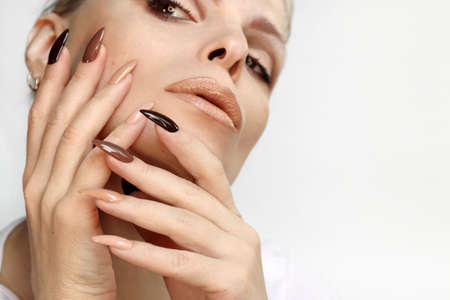Brown and beige make-up and manicure on the long shape of the nails of a woman.の写真素材