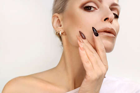 Brown and beige make-up and manicure on the long shape of the nails of a woman.の写真素材