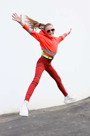 A girl jumps against the background of a wall in the city.の写真素材