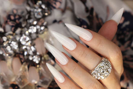 Long light manicure with jewelry on a woman's hand.の写真素材