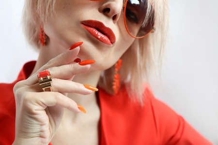Orange makeup and manicure on a blonde with sunglasses.の写真素材