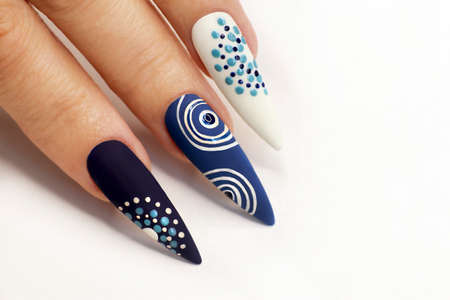 Manicure with a design of dots and circles on blue and white nail polish.の写真素材