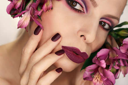Burgundy manicure and makeup on a girl with flowers.の写真素材