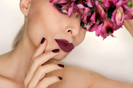 Burgundy manicure and makeup on a girl with flowers.の写真素材