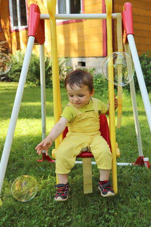 A child swings on a swing and plays with soap bubbles.の写真素材