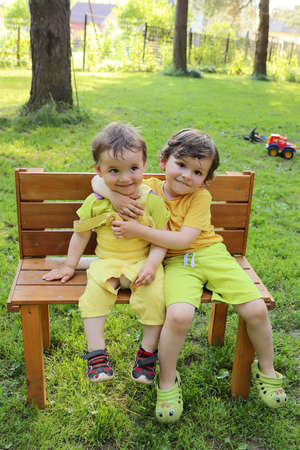 Little brothers communicate on a bench in the summer outdoors.の写真素材
