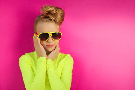 A blonde girl poses in a yellow turtleneck and sunglasses.の写真素材