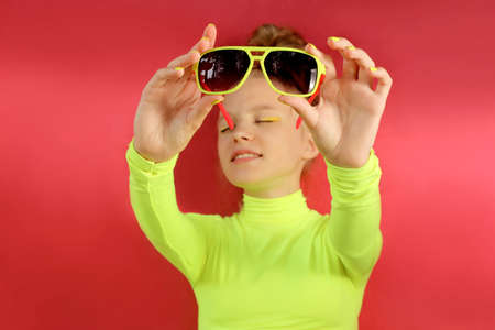 A blonde girl poses in a yellow turtleneck and sunglasses.の写真素材