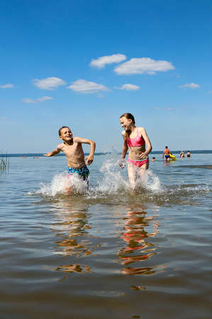 A boy and a girl play together in the lake in the summer.の写真素材