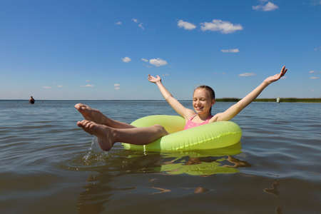 A child swims in the summer with a circle on the lake .