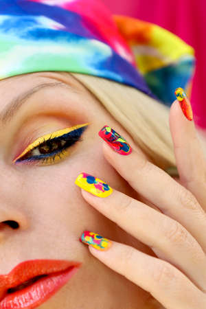 A model in a headscarf with a multicolored manicure and makeup.の写真素材