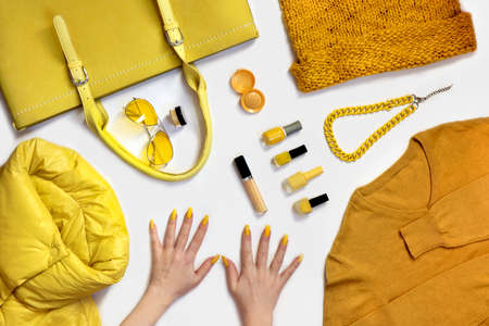 A collection of yellow fashionable wardrobe items with women's hands.