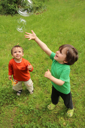 Two small children play with soap bubbles in nature in summer.の写真素材