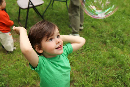 A little boy plays with soap bubbles in the summer outdoors.の写真素材