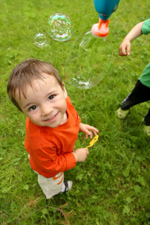 A little boy plays with soap bubbles in the summer outdoors.の写真素材