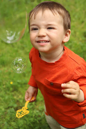 A little boy plays with soap bubbles in the summer outdoors.の写真素材