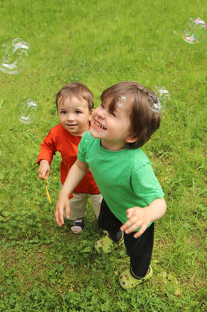 Two small children play with soap bubbles in nature in summer.の写真素材