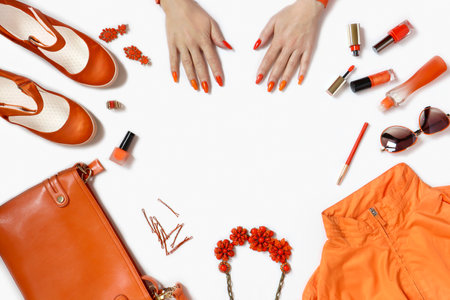 Women's hands with manicure and items of women's clothing and accessories in orange on a white background.の写真素材