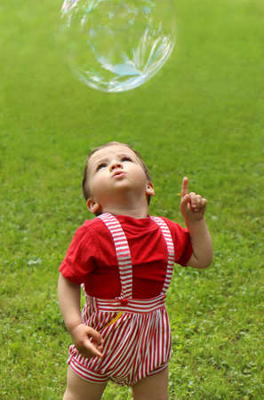 A child plays with soap bubbles in nature in summer.の写真素材