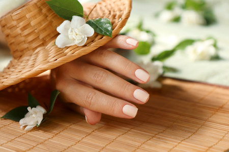 Light beige manicure on short nails with jasmine flowers.の写真素材