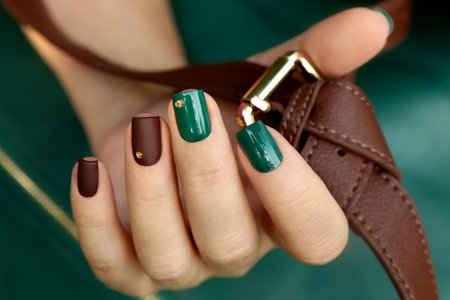 Green brown manicure on short nails with golden dots.の写真素材