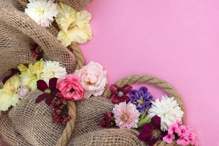 Flowers in burlap bag on pink background. flat lay.の写真素材