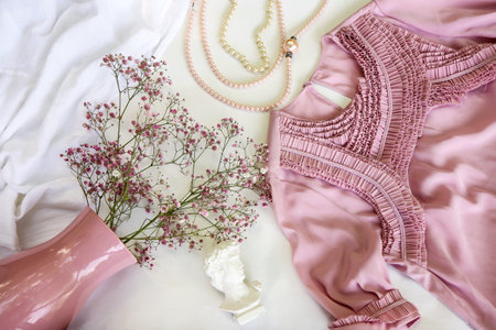 Aesthetic composition on a light background with a pink dress, a bouquet with gypsophila, beads.の写真素材
