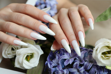 Female hands with white manicure and blue hyacinth flowers.の写真素材