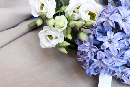 Flower arrangement of Eustoma flowers is white with blue Hyocinth on a linen background.の写真素材