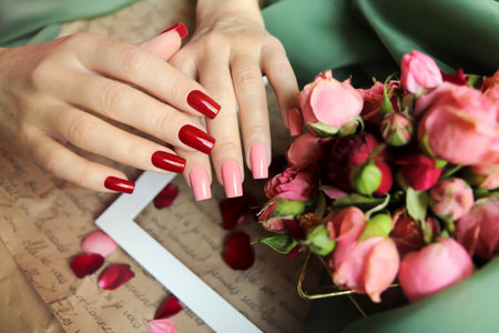 Manicure with pink and red nail polish on a square nail shape with a bouquet of roses.の写真素材