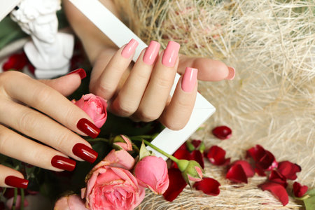 Manicure with pink and red nail polish on a square nail shape with a bouquet of roses.の写真素材