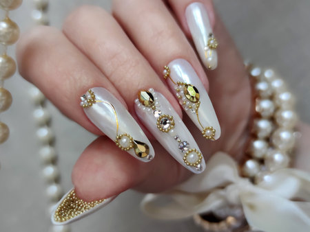 Female hand with long nails and white manicure holds a pearl necklaceの写真素材