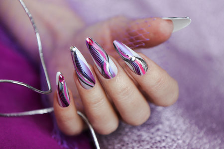 Long nail extensions with silver rhinestones and different colored lines.の写真素材
