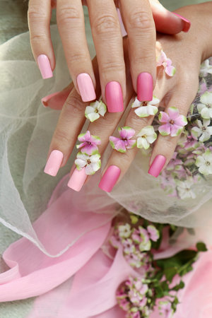 Nail extensions on a square shape with multi-colored pink nail polish.の写真素材