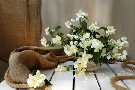Floral arrangement of Jasmine on a linen background with burlap and rope.の写真素材