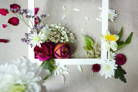 Floral arrangement with various beautiful flowers on a background of burlap and a white frame.の写真素材