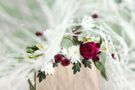 Beautiful bouquet of flowers in paper bag on white wooden backgroundの写真素材