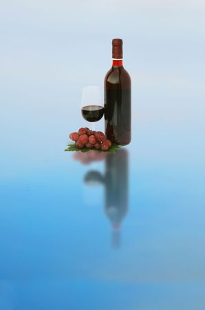 A wine bottle and a glass with grapesの写真素材